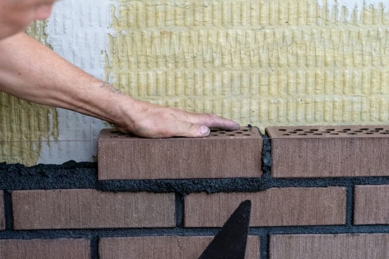 Bricklayer worker installing bricks on construction site